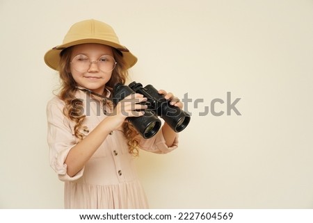 Traveler child. Child discoverer. Young researcher. Little girl in a safari hat with binoculars in her hands. Concept: search for adventure and treasure. Cute happy girl in safari clothes Royalty-Free Stock Photo #2227604569