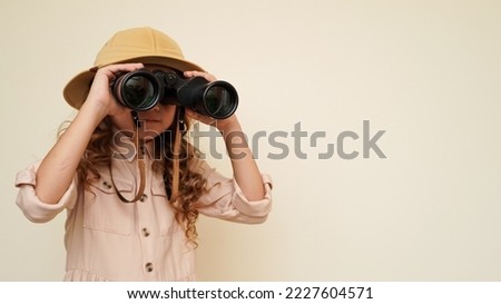 Traveler child. Child discoverer. Young researcher. Little girl in a safari hat with binoculars in her hands. Concept: search for adventure and treasure. Cute happy girl in safari clothes Royalty-Free Stock Photo #2227604571