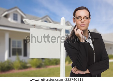 Attractive Serious Mixed Race Woman In Front of House and Blank Real Estate Sign.