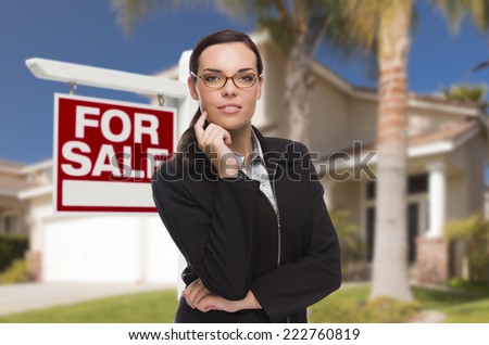 Attractive Mixed Race Woman in Front of House and For Sale Real Estate Sign.