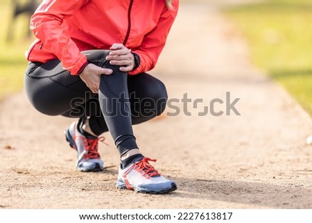 A young athlete sprained her knee while running, she holds it in pain. Royalty-Free Stock Photo #2227613817
