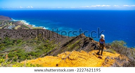 girl in a hat enjoys the oahu panorama from the top of the famous koko crater railway trailhead, oahu, hawaii, hiking in hawaii, holiday in hawaii Royalty-Free Stock Photo #2227621195