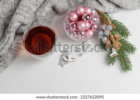  Christmas arrangement of pink balls for the Christmas tree, cups of black tea, decorated with a knitted gray sweater on a white table. Preparation for the holidays. High quality photo