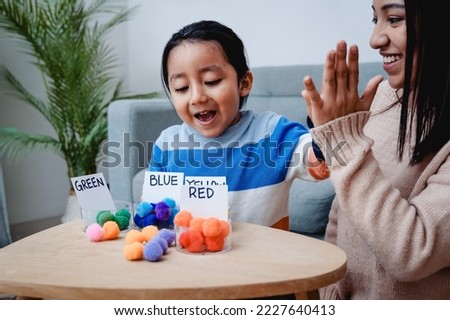 Asian mother and son having fun playing games together at home - Family homeschool concept - Focus on kid face. Royalty-Free Stock Photo #2227640413