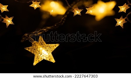 Merry Chrsitmas celebration decoration holiday background banner - Close-up of hanging golden star light chain on dark night sky with bokeh