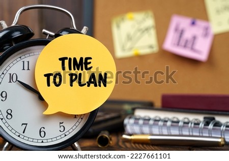Business concept. The alarm clocks have a sticker with the inscription - TIME TO PLAN. There are office items in the background in a blurry background.