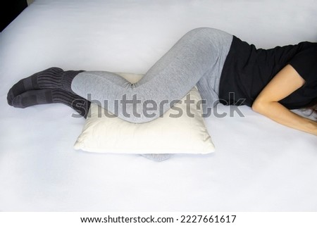 Leg cushion for sleeping for knee pain. Orthopedic pillow between the legs of a lying woman in pajamas. Royalty-Free Stock Photo #2227661617