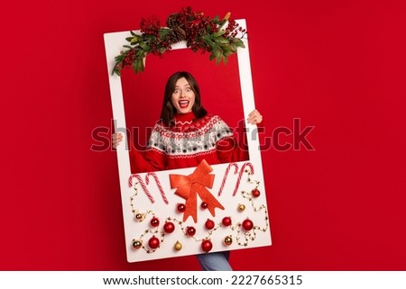 Portrait of crazy overjoyed girl arms hold decorated xmas album card isolated on red color background