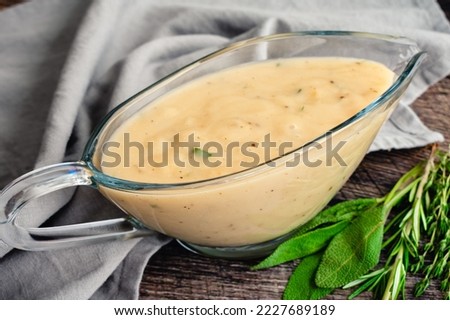 Classic Southern Gravy Made with Fresh Herbs in a Gravy Boat: Homemade gravy in a glass gravy boat with fresh herbs on the side Royalty-Free Stock Photo #2227689189
