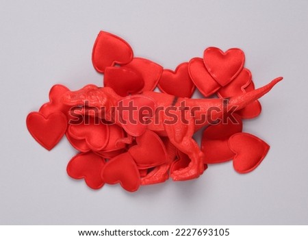 Toy dinosaur with hearts on gray background. Love, romance, valentine's day, February 14 concept