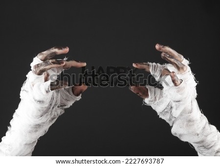 Mummy's hand wrapped in bandage holds word Happy Halloween isolated on black background. Halloween concept