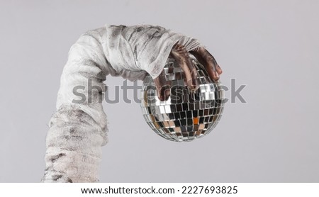 Mummy hand holding disco ball isolated on black background. Halloween concept