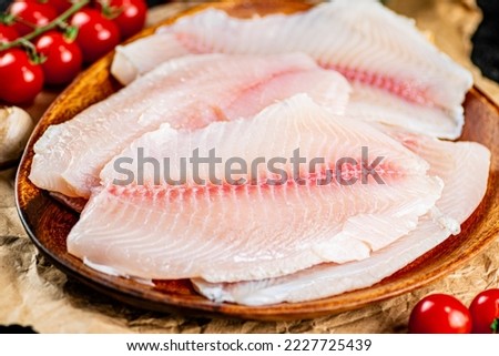 Raw fish fillet on a plate with a branch of tomatoes. Macro background. High quality photo