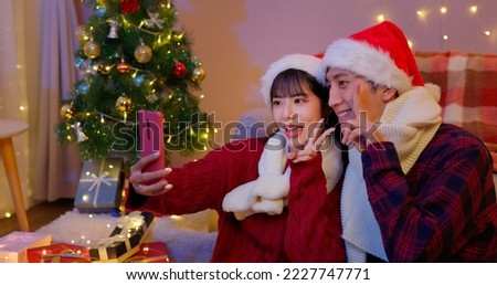 asian lovely young couple wearing christmas clothes are taking selfie with xmas tree at home