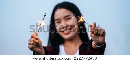 Selective focus, Hand of Asian beautiful woman holding fireworks burning sparkler playing celebration in New year festival, Dressed in plaid shirt, smile and looking at camera, copy space