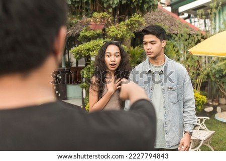 An emotional man catches his girlfriend with another man. Confronting a cheating and unfaithful couple. Royalty-Free Stock Photo #2227794843