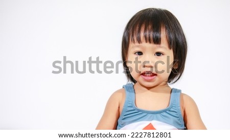 Studio shot of little beautiful kindergarten Asian baby girl daughter model in cute gray shark costume swimsuit outfit sitting on white background