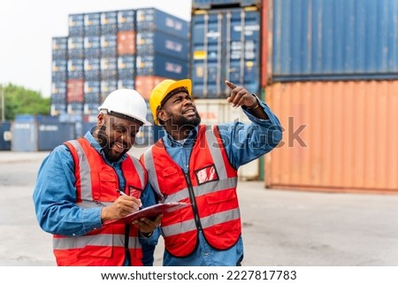 Portrait photo of the moment of two black african male container engineers working and inspecting containers around a shipping yard of a local logistic freight  forwarder company Royalty-Free Stock Photo #2227817783
