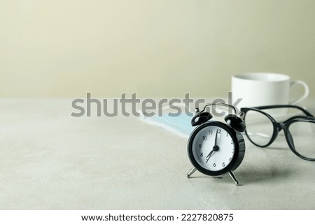 Morning coffee concept with alarm clock, glasses and mask