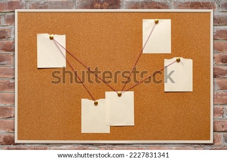 The detective's corkboard is hanging on a brick wall. Copy space. Royalty-Free Stock Photo #2227831341