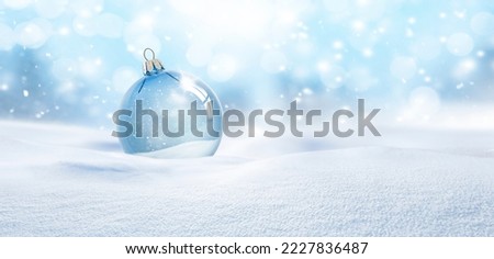 Transparent glass Christmas ball in the snow