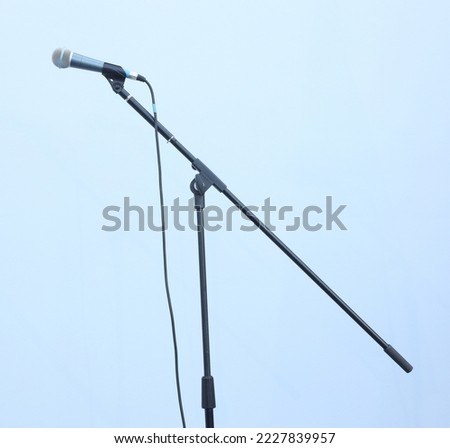 Black microphone with cord against light wall concept photo. Talk speaker show scene
