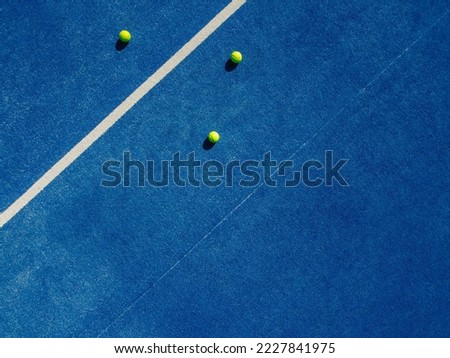 Overhead aerial view of three balls near the net of a blue paddle tennis court, sports courts Royalty-Free Stock Photo #2227841975
