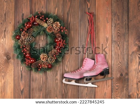 christmas wreath and old ice skates on wooden wall