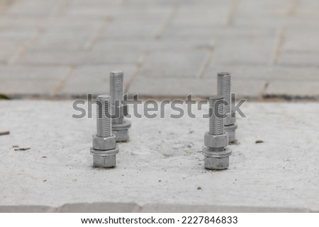 Closeup Anchorage bolt and nut which embedded in concrete structure etail of bolts. Steel plate based on anchor bolts on the concrete pillar. Bolts base Blurred soft focus, Bolts base select focus.
