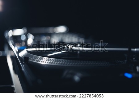 DJ turntable plays vinyl record with music on party in nightclub. Professional disk jokey audio equipment in close up Royalty-Free Stock Photo #2227854053