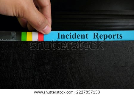 Hand picking incident report file in black binder folder. Corporate business concept. Royalty-Free Stock Photo #2227857153