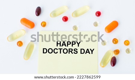 Happy Doctors Day text on a yellow card on a white background scattered around are multi-colored talettes. Medical concept