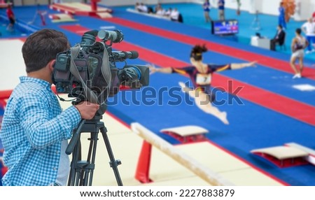 Camera shooting live broadcast from gymnastics game to television and internet on the background blured Unidentified women gymnast