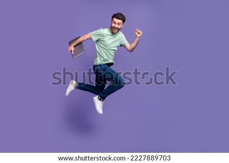Full size photo of handsome young man running fast jump hold laptop dressed stylish gray clothes isolated on purple color background Royalty-Free Stock Photo #2227889703