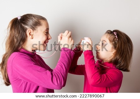 Couple of Little Girls Taking Picture Using Toy Photo Camera on white background