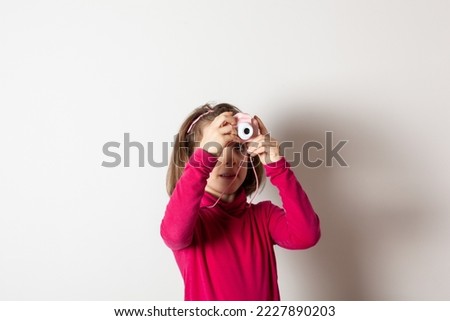 Little Girl Taking Picture Using Toy Photo Camera on white background