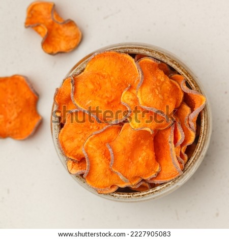 Healthy organic sweet potato chips in a bowl on a stone background. Vegetarian and vegan appetizer. Diet. A useful snack. Selective focus, top view, square picture