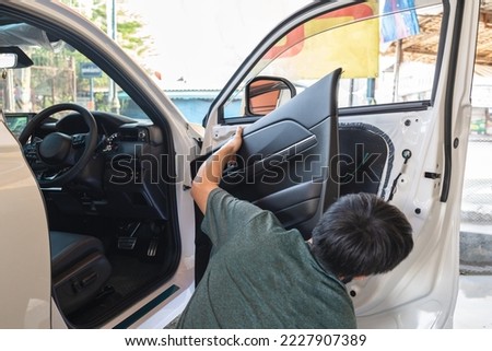 Mechanic man unpacking and assemble vehicle door part for checking car problem or installing speaker in garage workshop Royalty-Free Stock Photo #2227907389