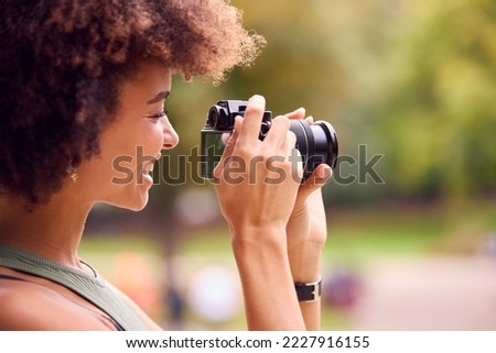 Young Woman Outdoors With DSLR Camera Taking Photos In City Park