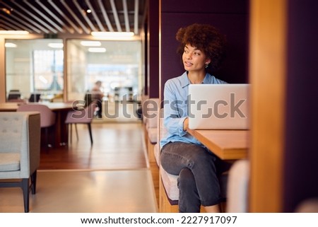 Young Businesswoman In Modern Open Plan Office Working On Laptop In Seating Pod Royalty-Free Stock Photo #2227917097