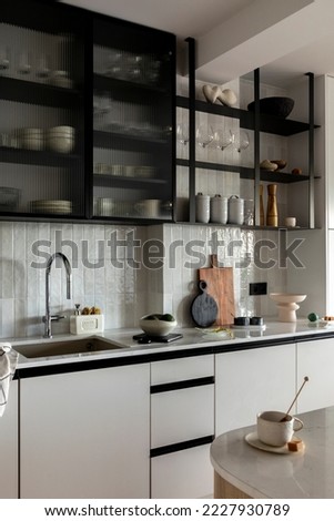 Creative interior design of kitchen space with gray cabinets, simple silver faucet, cutting board, sink, glass cabinets, fruit bowl,  and kitchen accessories. Home decor. Template. 
