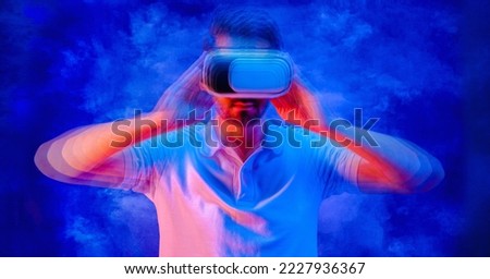 blured man with goggle headset of virtual reality on neon blue background in concept of future vr technology