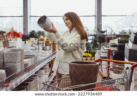 A woman chooses a pot for home plants in a greenhouse store, hardware store, shopping for home and interior goods. Royalty-Free Stock Photo #2227936489