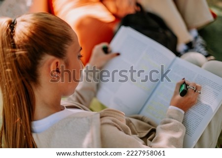 A blonde female teenager is sitting in a coffee bar on a lazy bag, underlining important parts Royalty-Free Stock Photo #2227958061