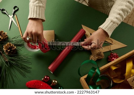 Top view hands hold a white ribbon over red wrapping paper Packing Christmas and New Year gifts. Boxing day. Happy holiday present, surprise. Magic time. Celebration winter event. Handwork art craft