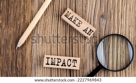 MAKE AN IMPACT words on a wooden building blocks on the wooden background