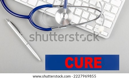 CURE word with Stethoscope on a keyboard on grey background
