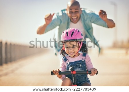 Excited father teaching girl to ride a bike in sunshine, summer fun and beach promenade outdoors. Happy kid, learning and riding bicycle with help from dad, parent and safety for healthy development Royalty-Free Stock Photo #2227983439