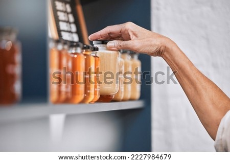 Honey, product and retail with hands of woman for natural, supermarket and grocery shopping shelf. Food, health and sustainability with organic store employee for small business, sale and choice Royalty-Free Stock Photo #2227984679