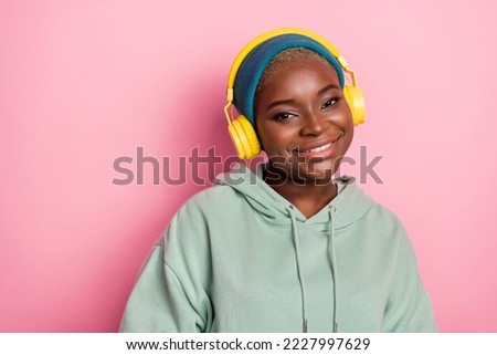 Portrait of good mood pretty fashionable girl wearing headphones over beanie isolated on pink color background